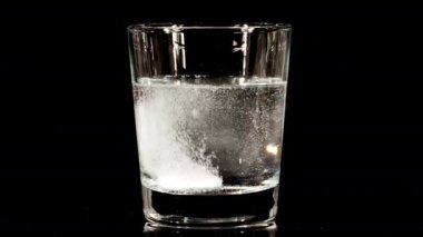 Siyah arka planda suyla birlikte bardağa düşen aspirin. Fışkırtıcı tablet aspirin. Tıp konsepti, sağlık, tedavi. Yavaş çekim