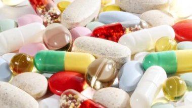 Renkli tıbbi haplar beyaz arka planda dönüşümlü olarak kullanılıyor. Haplar, vitaminler ve ilaçlar. İlaç Endüstrisi. Tıp konsepti. Makro atış. Yavaş çekim