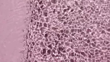 Su yüzeyi üst görünümü. Su pembe renkte sıçrıyor. Saf mavi su, güneş ışığını yavaş çekimde yansıtıyor. Güneş ve gölgeler. Hareket temiz yüzme havuzu dalgalanmaları ve el sallama. 4k