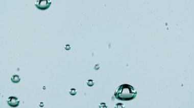 Açık mavi arka planda yükselen suyun içindeki makro hava kabarcıkları. Yavaş çekim.