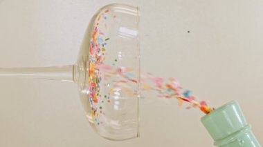 Renkli şekerler, yeşil arka planda şarap bardağına dökülen şekerlemeler. Tatil konsepti, doğum günü partisi, Noel, Yeni Yıl.