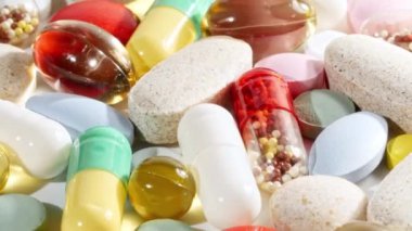 Renkli tıbbi haplar beyaz arka planda dönüşümlü olarak kullanılıyor. Haplar, vitaminler ve ilaçlar. İlaç Endüstrisi. Tıp konsepti. Makro atış. Yavaş çekim