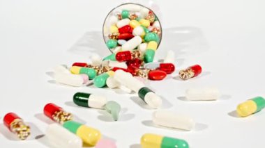 Beyaz arka plandaki masaya düşen farklı tıbbi ilaçların yakın çekimi. Kapsüller, vitaminler ve ilaçlar. İlaç Endüstrisi. Tıp konsepti. Makro atış. Yavaş çekim