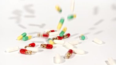 Beyaz arka plandaki masaya düşen farklı tıbbi ilaçların yakın çekimi. Kapsüller, vitaminler ve ilaçlar. İlaç Endüstrisi. Tıp konsepti. Makro atış. Yavaş çekim