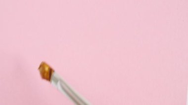 Pembe arka planda izole edilmiş altın fırça darbeleri. Altın boya lekesi dokusu. Altın renkli, dokulu, sanatsal çizim. Kozmetik kokuları.
