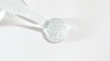 Şeffaf Mavi Kozmetik Sıvı Jel 'in Macro Çekimi, Beyaz Yüzeyde Pipette Damlaları İçinde Köpüklü Krem. Güzellik derisi ürün örneği. Organik kozmetik, ilaç. Cilt Bakımını Göster.