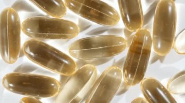 Sarı kapsüller tıbbi haplar, yakın çekim dönüşümlü. C vitamini, Omega 3 yağ kapsüllerinde. Haplar ve uyuşturucular. İlaç Endüstrisi. Tıp konsepti. Yavaş çekim