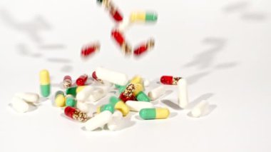 Beyaz arka plandaki masaya düşen farklı tıbbi ilaçların yakın çekimi. Kapsüller, vitaminler ve ilaçlar. İlaç Endüstrisi. Tıp konsepti. Makro atış. Yavaş çekim