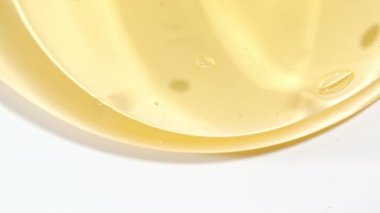 Şeffaf Sarı Kozmetik Sıvı Jel 'in Macro Shot' u, Beyaz bir yüzeye dökülen köpüklü Krem. Doğal Organik Kozmetik, Tıp.