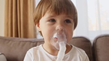Maske takan küçük bir kız ciğerlerine duman ilacı soluyor. Çocuk evde astım spreyinden nefes alıyor.