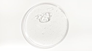 Şeffaf Kozmetik Sıvı Petri 'nin cam kasesine damlıyor. Makro Kozmetik Serumu, Hyalurinik asit. Cilt Bakımını Göster.