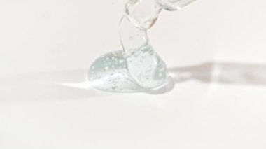 Sıvı mavi jel ya da beyaz bir yüzeye damlayan pipette serum. Yukarıdan köpüklü kozmetik sıvısı için damlatıcı.