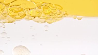 Yavaş Hareket Eden Sarı Altın Yağ, Açık Beyaz Arkaplanda yükselen Sudaki Hava Kabarcıkları. Kabarcıklı şeffaf kozmetik jel sıvısı. Makro Vuruş.
