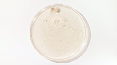 Şeffaf Kozmetik Sıvı Petri 'nin cam kasesine damlıyor. Makro Kozmetik Serumu, Hyalurinik asit. Cilt Bakımını Göster.