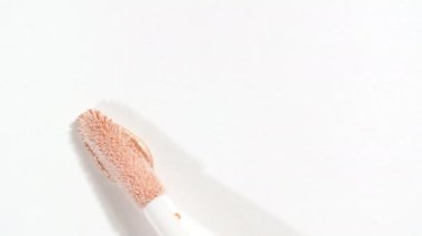 Makro çekim ve ağır çekim fırça, aplikatör, leke, kapatıcı beyaz arka planda izole edilmiş. Profesyonel kozmetik reklamı. Kozmetik Sıvı Temelinin Kapanışı.