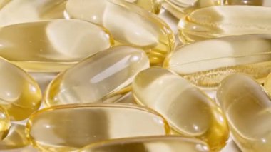 Sarı kapsüller tıbbi haplar, yakın çekim dönüşümlü. C vitamini, Omega 3 yağ kapsüllerinde. Haplar ve uyuşturucular. İlaç Endüstrisi. Tıp konsepti. Yavaş çekim