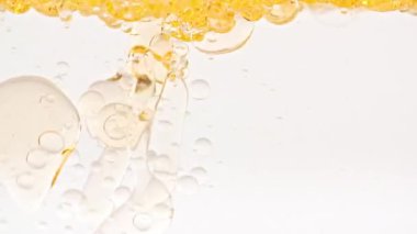 Yavaş Hareket Eden Sarı Altın Yağ, Açık Beyaz Arkaplanda yükselen Sudaki Hava Kabarcıkları. Kabarcıklı şeffaf kozmetik jel sıvısı. Macro Shot. Yüksek kaliteli FullHD görüntüler