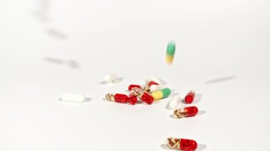 Beyaz arka plandaki masaya düşen farklı tıbbi ilaçların yakın çekimi. Kapsüller, vitaminler ve ilaçlar. İlaç Endüstrisi. Tıp konsepti. Makro atış. Ağır çekim. Yüksek kalite FullHD 