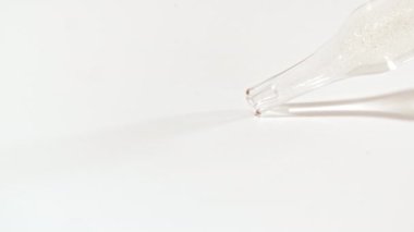 Sıvı sarı jel ya da beyaz bir yüzeye damlayan pipette serum. Yukarıdan köpüklü kozmetik sıvısı için damla. Yüksek kalite 4k görüntü
