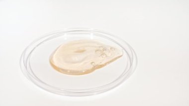 Şeffaf Kozmetik Sıvı Petri 'nin cam kasesine damlıyor. Makro Kozmetik Serumu, Hyalurinik asit. Cilt Bakımını Göster.