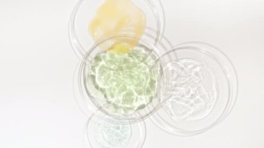Beyaz arka planda kozmetik numuneleriyle Petri kaplarının rotasyonu. Şeffaf jel sıvısı, köpüklü krema. Kimyasal laboratuvar araştırması. Doğal organik kozmetik, ilaç. 4k