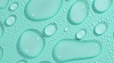 Yeşil-mavi pastel arka planda Makro Kozmetik Nemlendirici Sıvı. Şeffaf kozmetik jel sıvısı rotasyonu, Hyaluronic asit. Yüksek kalite 4k görüntü