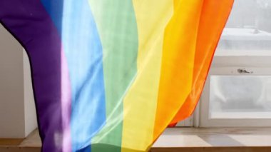 Gökkuşağı LGBT bayrağı elinde ve gün batımında güneş ışınlarıyla dalgalanıyor. Lezbiyen, gey, biseksüel, transseksüel sosyal hareketler.