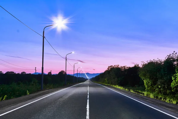 Podmiejska Droga Asfaltowa Wieczorem Oświetlona Lampami Ulicznymi — Zdjęcie stockowe