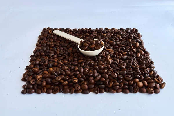 Kahve çekirdekleri ve arka planda plastik kaşık..