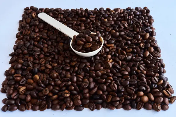 Kahve çekirdekleri ve arka planda plastik kaşık..