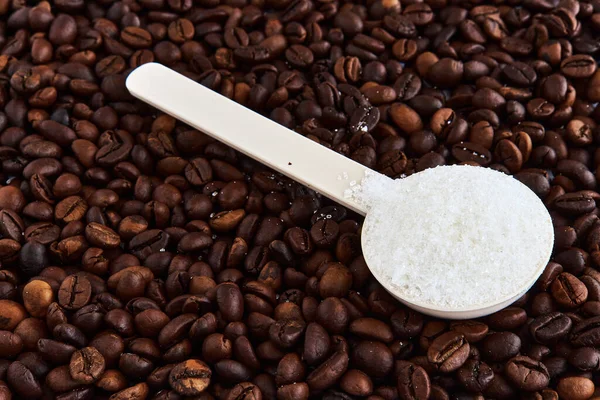 Kaşık içinde şeker ve masaya serpiştirilmiş kahve.