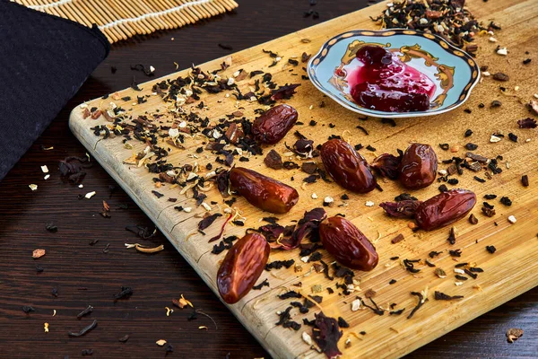 Kesme tahtasındaki kurutulmuş tarihler, bir tabakta reçel ve serpiştirilmiş çay..