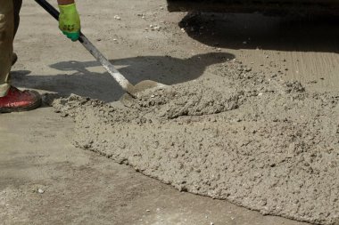 Yoldan gelen bir kürekle havan topunu temizliyorum. Dökülen çimentoyu temizliyorum. Bir işçinin elinde kürek..