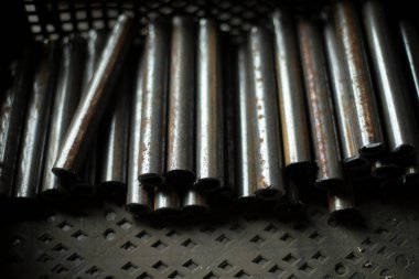 Metalden yapılmış borular kesilmiş. Bir sürü çelik tüp. Atölyede kurusıkı var. Demir kütük profili.