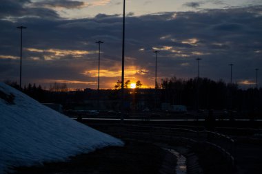 Sokakta gün batımı. Akşam oldu. Gri bulutlar arasında sarı ışık kaynağı. Şehrin manzarası..