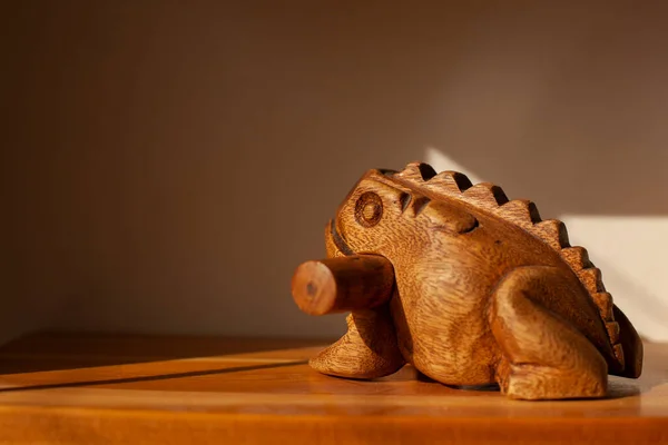 Wooden frog. Musical instrument made of wood. Stick and frog with teeth to extract sound. Noise instrument Toad Figure.