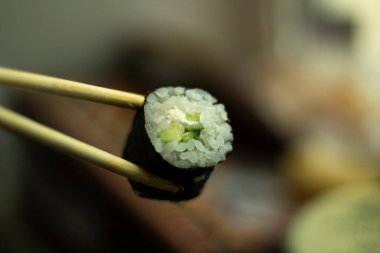 Suşi sopayla tutulur. Pirinç ve salatalıklı suşi. Asya mutfağı. Taze yemek..