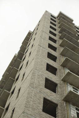 İnşaat halindeki evin pencereleri. Şehirde bir bina inşaatı. Bir apartman inşaatı. Bina hatsız. Pencere çerçevesi olmayan boş pencereler.