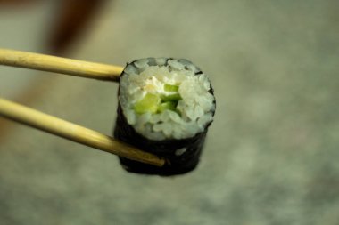 Suşi sopayla tutulur. Pirinç ve salatalıklı suşi. Asya mutfağı. Taze yemek..