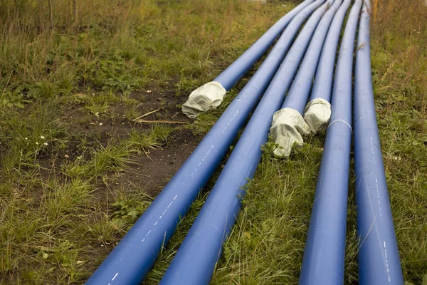 Blue water pipes. Industrial pipes lie on the ground. Details of laying pipes with gas. Sewer repair.