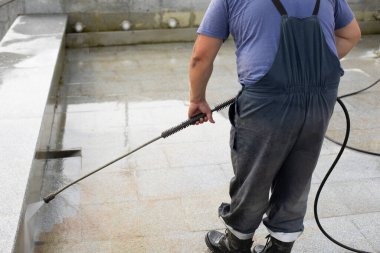 İşçi yüzeyi pasdan yıkar. Adam, suyun basıncıyla kiri temizler. Şehir hizmetleri fıskiyeyi temizliyor. Adam çalışıyor..