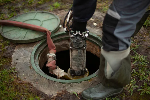 排污机修理 工人把设备放进下水道的舱口 在地下水供应系统中安装消防栓 — 图库照片