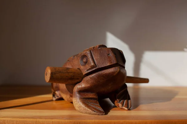 Wooden frog. Musical instrument made of wood. Stick and frog with teeth to extract sound. Noise instrument Toad Figure.