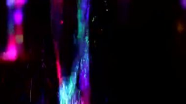 Colored stream of water on dark background. Fountain at night. Jet of water rises up in turbulent stream. Illumination of fountain at night. Video shooting of monotonous movement of liquid.