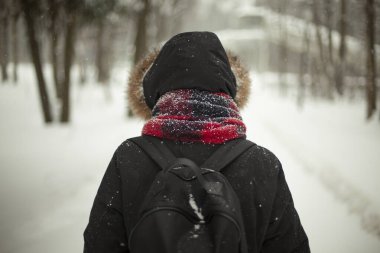 Kış giysileri Kapüşonlu bir kız. Sokakta eşarplı bir adam. Siyah ceket. Kışın yürü.