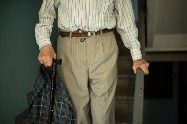 Emekli merdivenlerden aşağı iniyor. Büyükbaba merdivenlerden iniyor. Rusya 'daki yaşlı adam. El parmaklıklara tutunuyor..