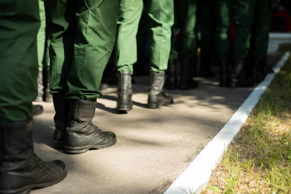 Military stands in row. Soldiers\' shoes. Boots and military uniforms. Formation of military personnel.