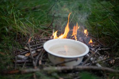 Turist yangını. Isıtma suyu yanıyor. Açık ateşte sıvı bulaşık. Ormanda yemek pişirmek. Ormanda kaynayan nehir suyu.