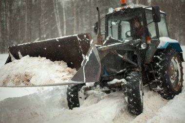 Traktör karı kaldırır. Kışın ağır makineler. Kova dolusu buz. Yol temizleniyor.