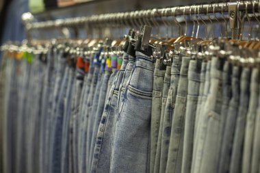 Kot pantolon mağazada. Elbiseler askıda asılı. Kot pantolon satışı. Ticaret katının ayrıntıları.